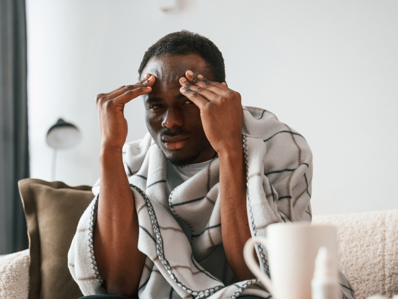 An ill man holding his head and wondering the difference between flu and hay fever
